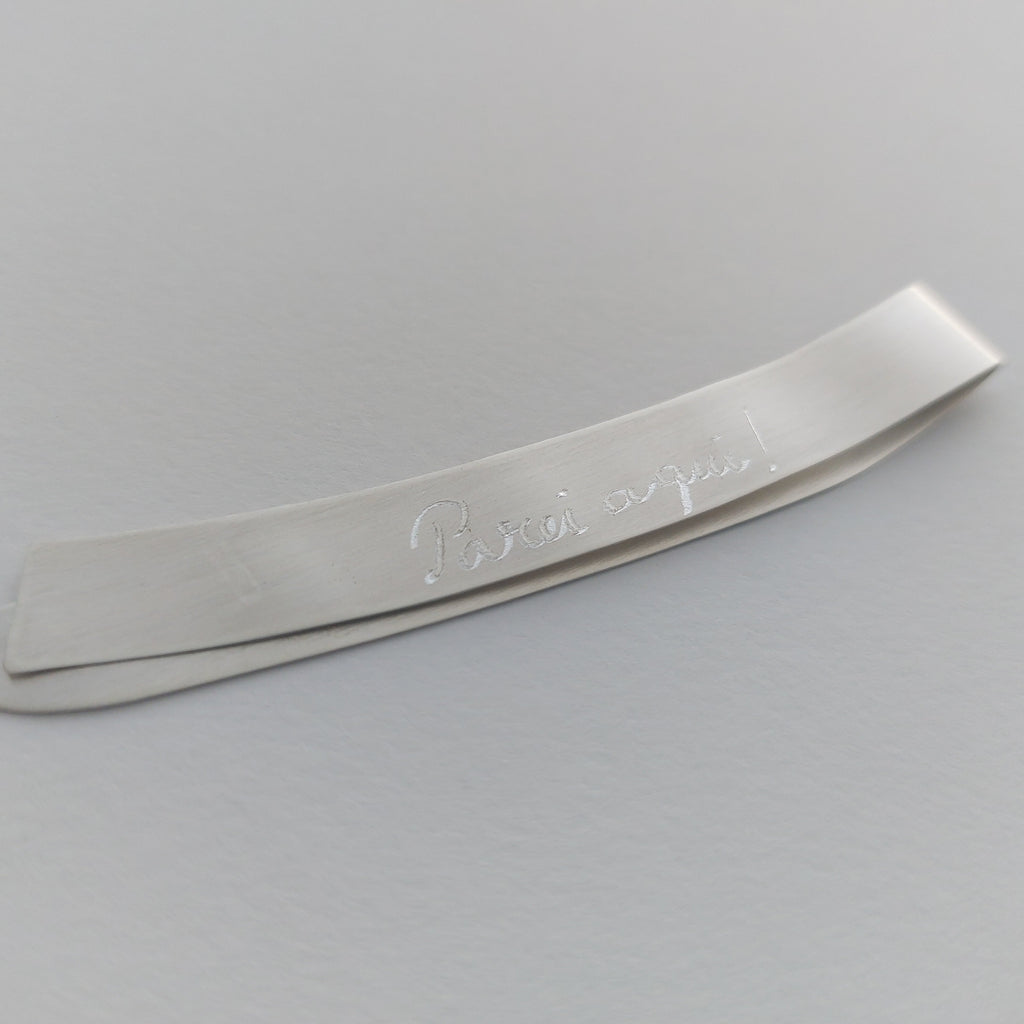 Metallic object with engraved text on a gray background