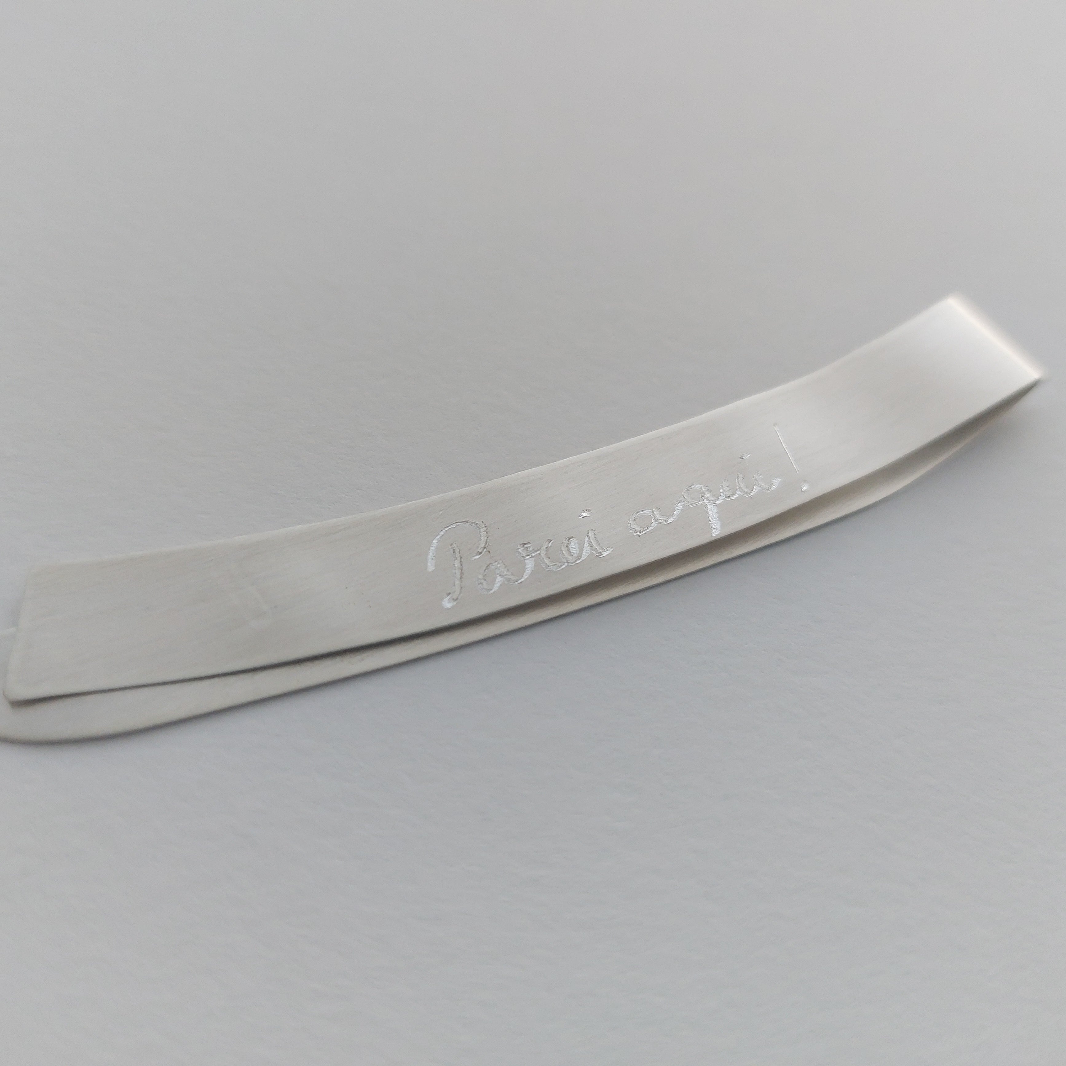 Metallic object with engraved text on a gray background