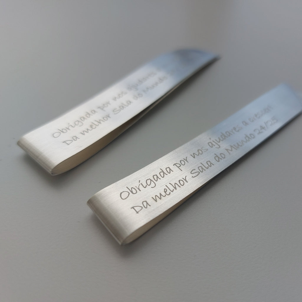 Two metallic bookmarks with engraved text on a light gray background