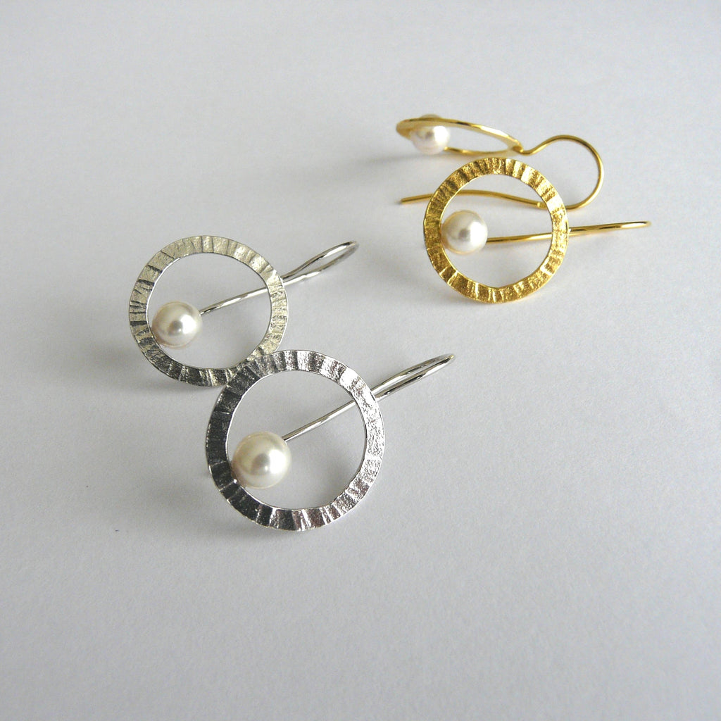 Three pearl earrings in different designs on a light gray background