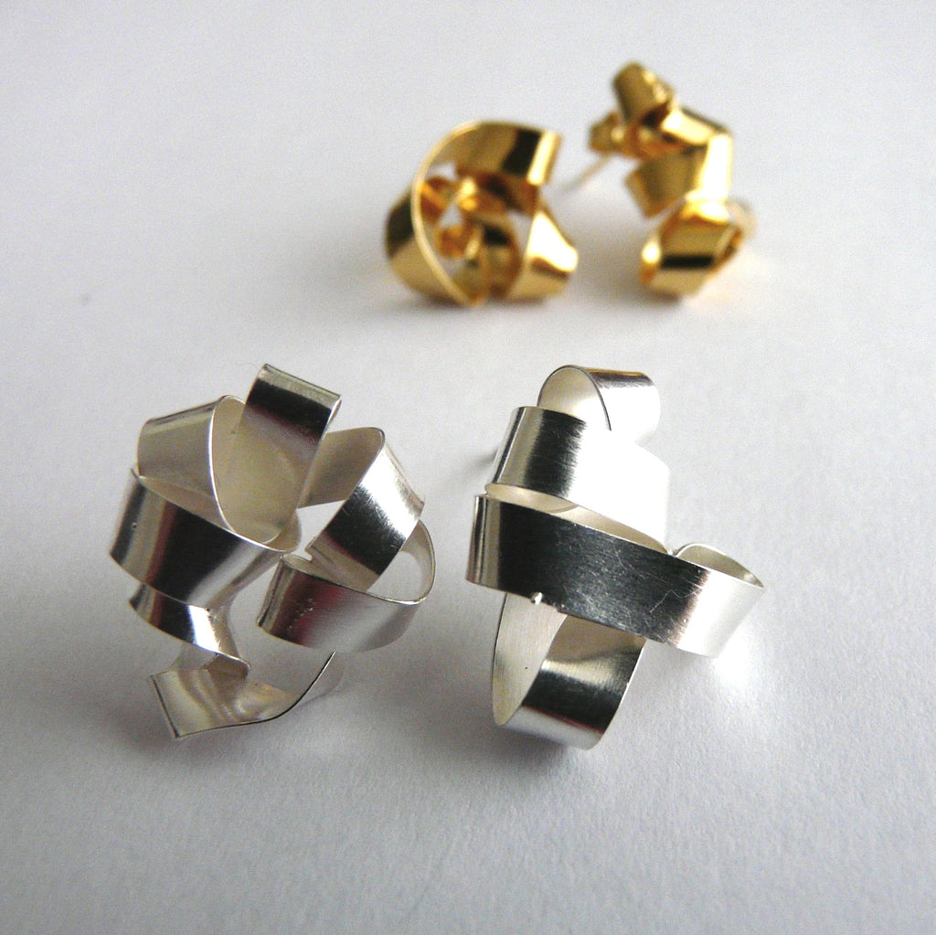 Pair of silver geometric earrings on a light gray background
