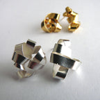 Pair of silver geometric earrings on a light gray background