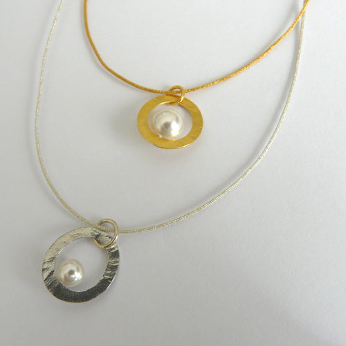 Two necklaces with circular pendants featuring pearls on a white background