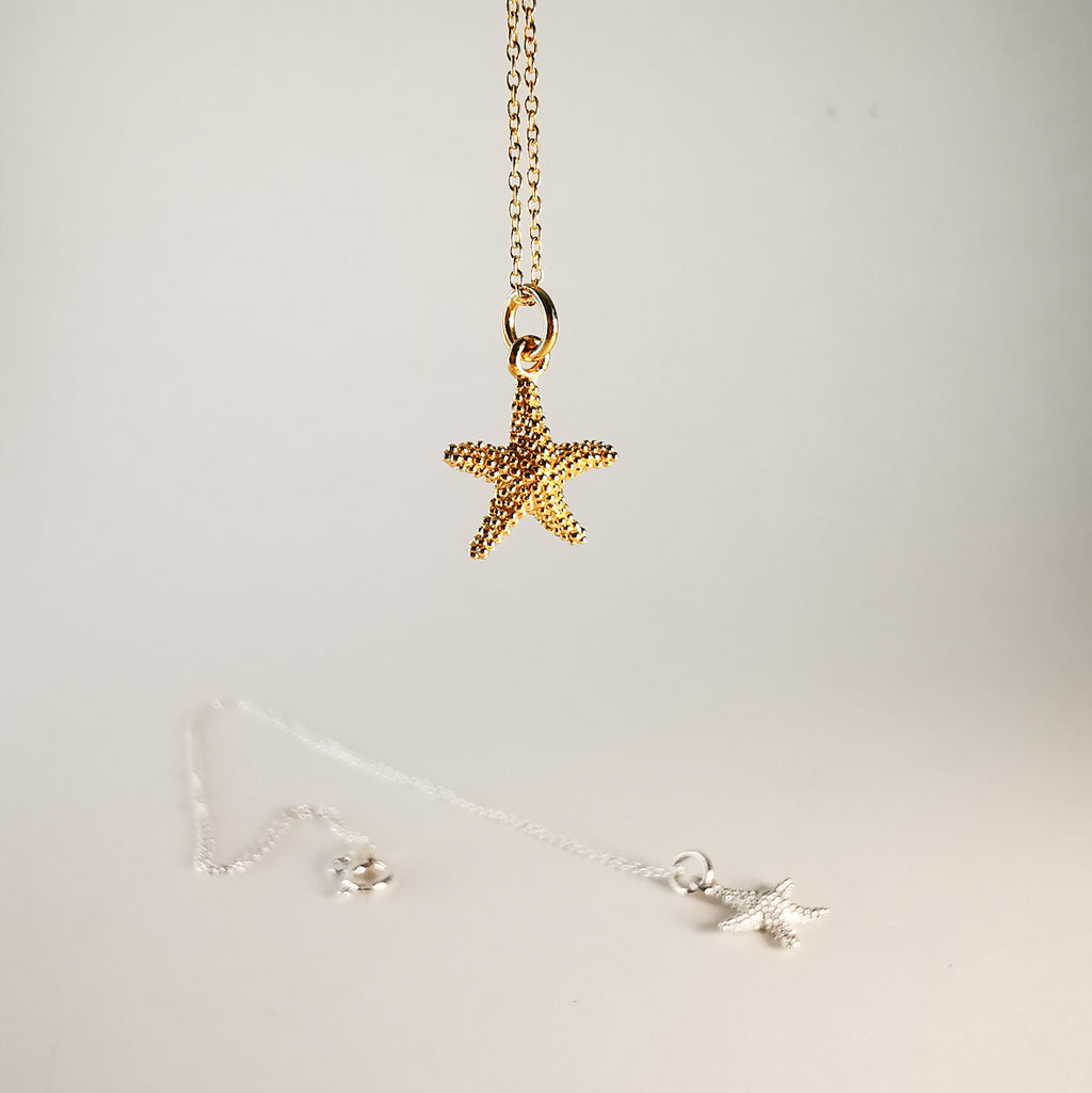 Gold starfish pendant necklace on a light gray background