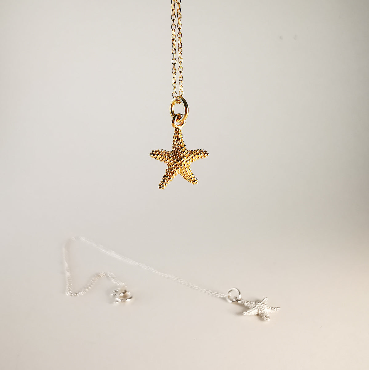 Gold starfish pendant necklace on a light gray background