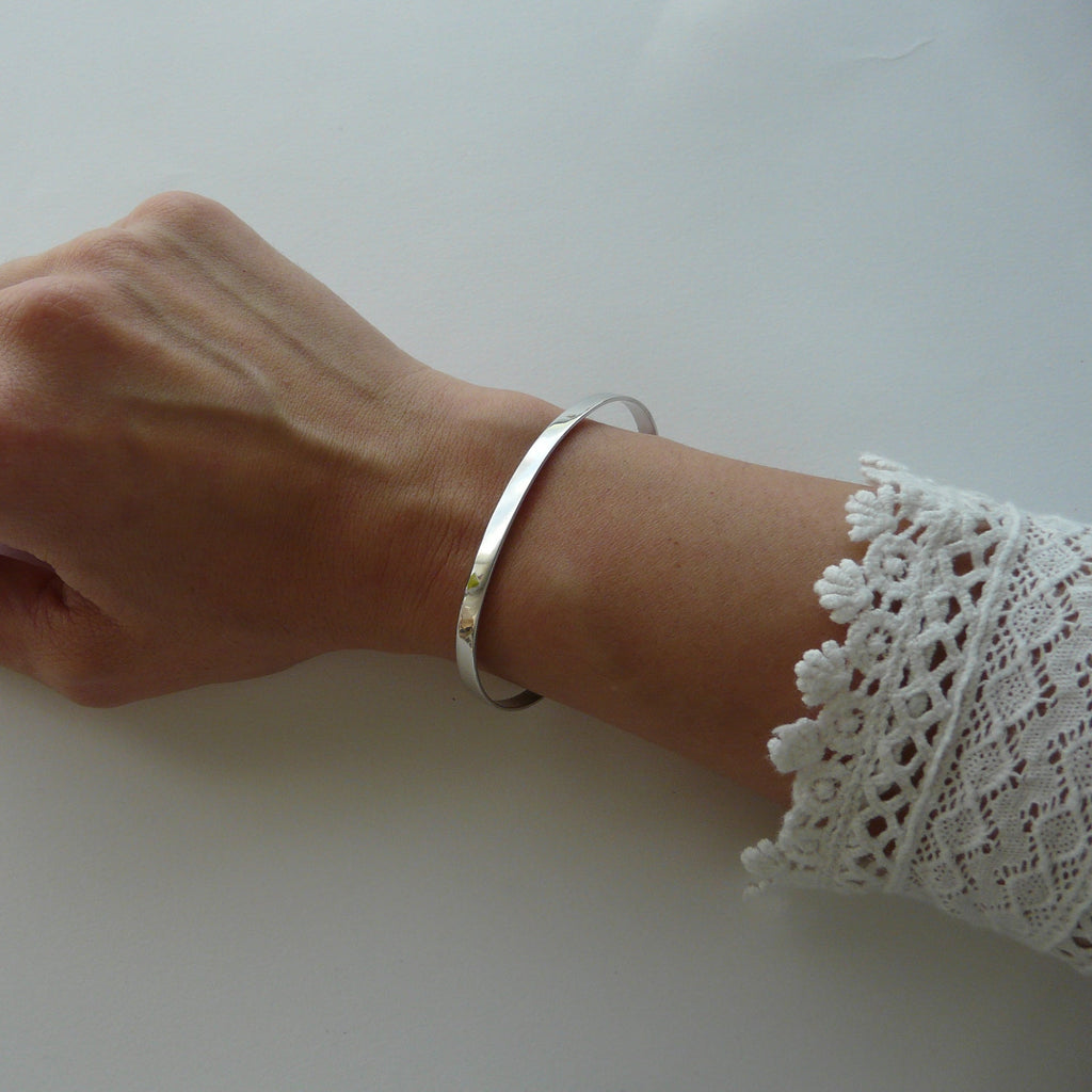 Hand wearing a silver bracelet on a white background