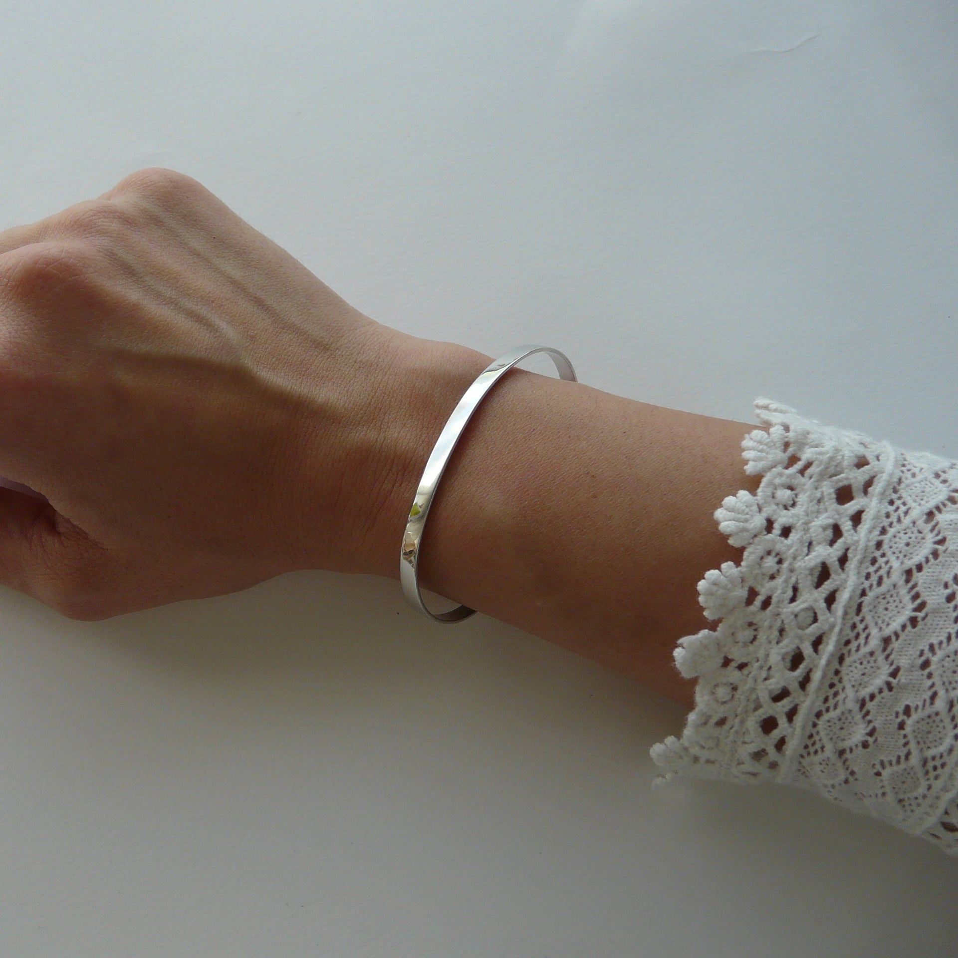 Hand wearing a silver bracelet on a white background