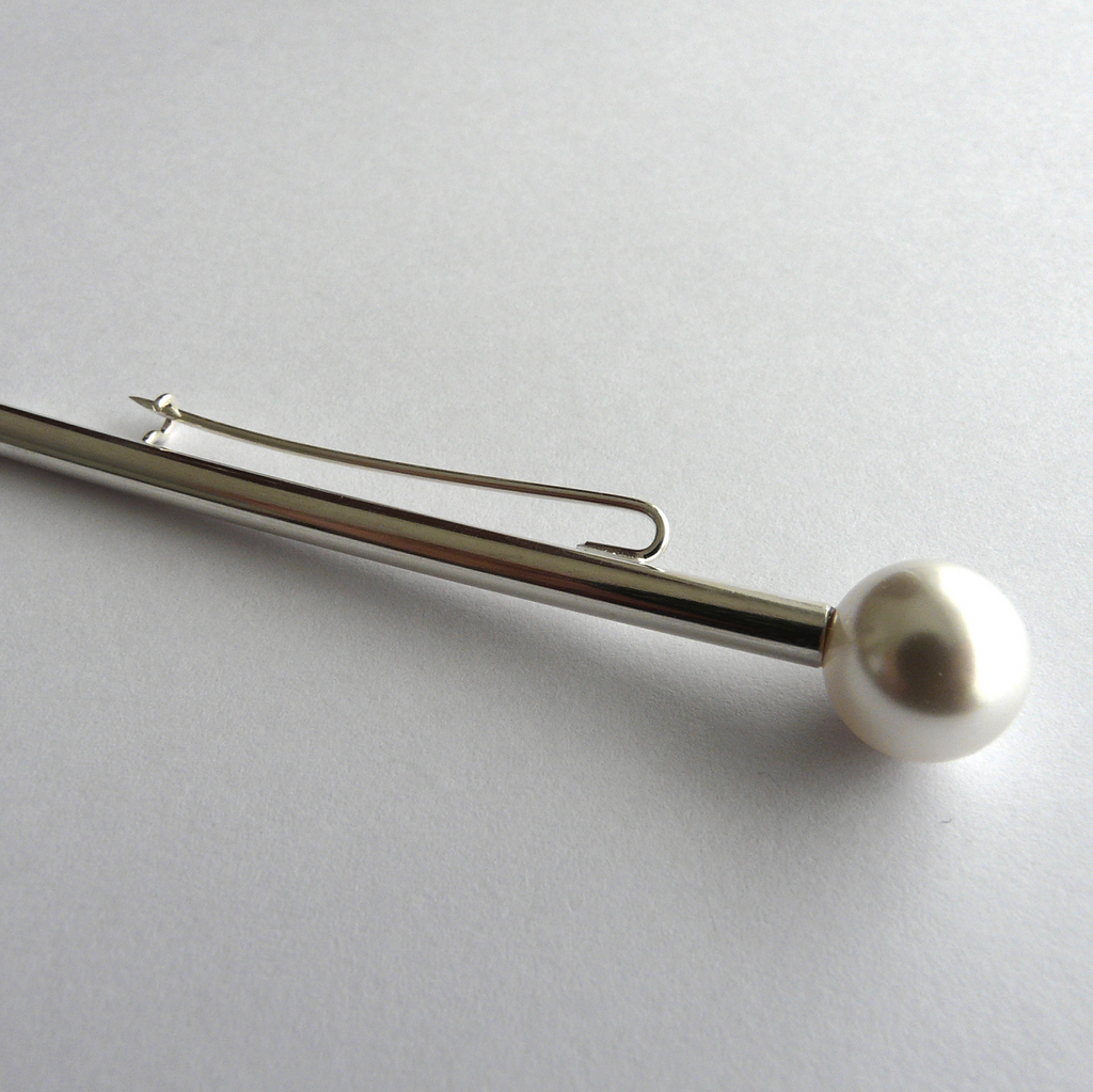 Silver hair clip with a pearl on a light gray background