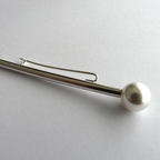 Silver hair clip with a pearl on a light gray background