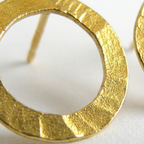 Gold circular earring on a white background