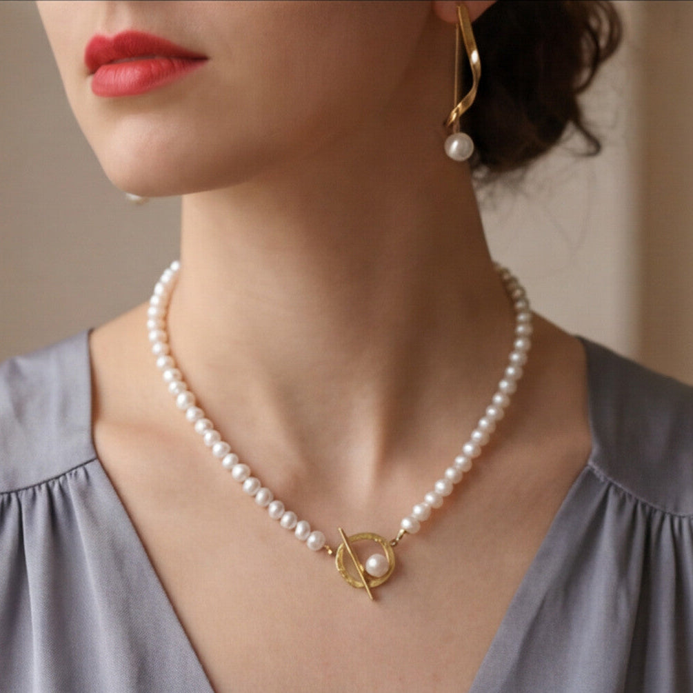 Woman wearing a pearl necklace and earrings against a neutral background