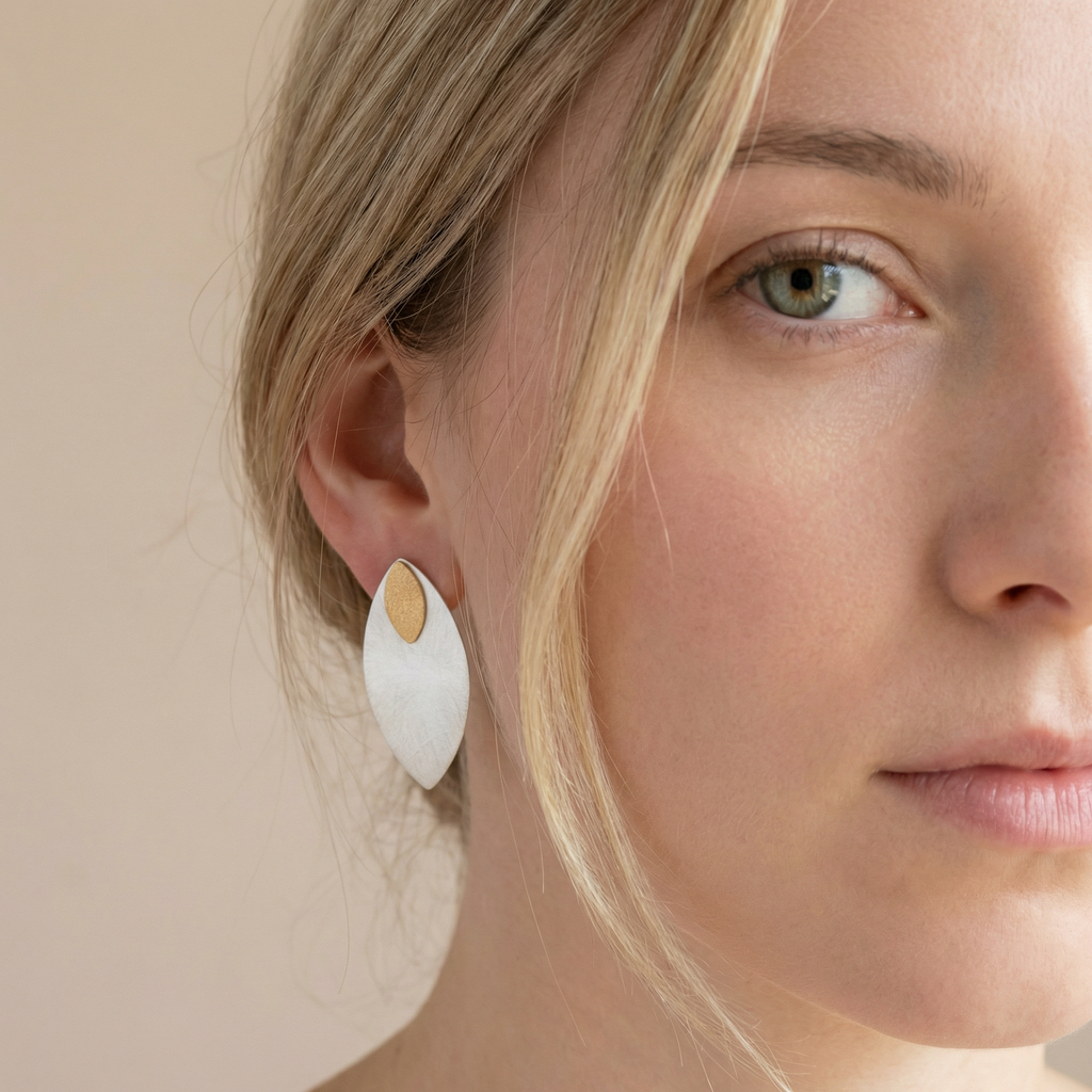 Close-up of a woman wearing a white teardrop earring with a gold accent.