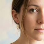 Close-up of a woman wearing gold earrings with a blurred background